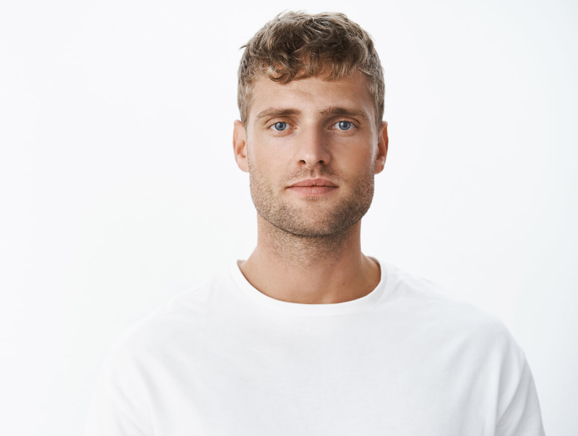 waist-up-shot-handsome-calm-blond-blue-eyed-guy-with-bristle-white-t-shirt-looking-front-with-relaxed-carefree-facial-expression-posing-gray-wall-looking-sincere-chill 1-1